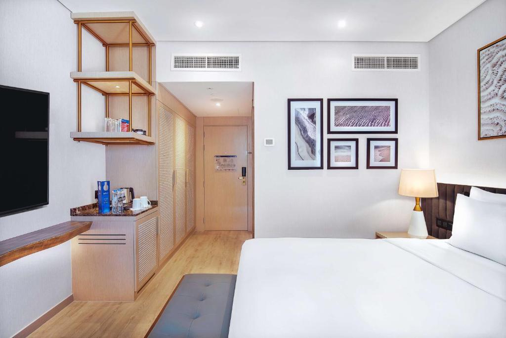 a bedroom with a white bed and a tv at Radisson Blu Hotel & Resort, Abu Dhabi Corniche in Abu Dhabi
