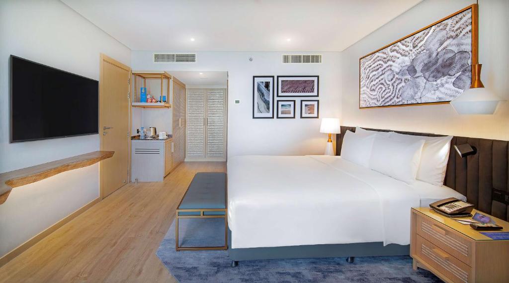a hotel room with a large bed and a flat screen tv at Radisson Blu Hotel & Resort, Abu Dhabi Corniche in Abu Dhabi