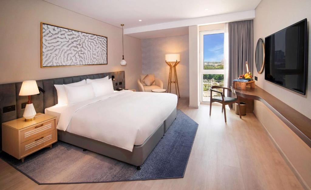 a bedroom with a bed and a desk and a television at Radisson Blu Hotel & Resort, Abu Dhabi Corniche in Abu Dhabi