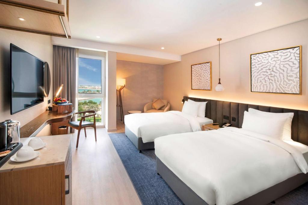 a hotel room with two beds and a television at Radisson Blu Hotel & Resort, Abu Dhabi Corniche in Abu Dhabi