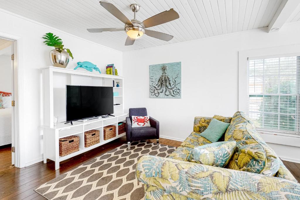 uma sala de estar com um sofá e uma televisão de ecrã plano em Kissing Palms em Panama City Beach