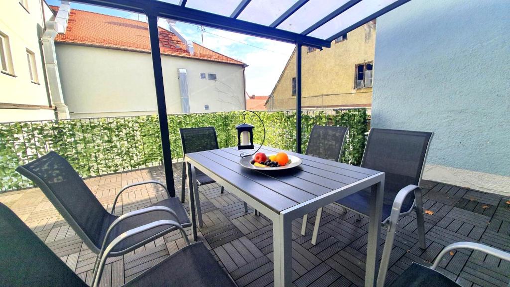 a table and chairs on a balcony with a bowl of fruit at Neuburg Ferienwohnung am Schloss in Neuburg an der Donau