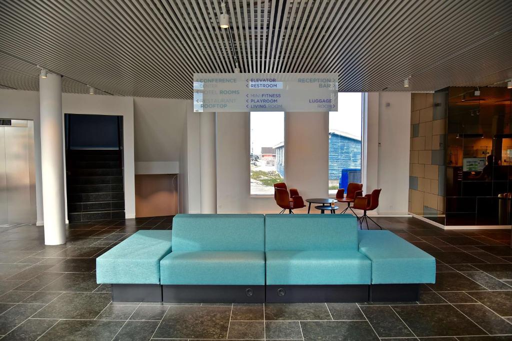 a blue couch in a lobby with a table and chairs at Best Western Plus Hotel Ilulissat in Ilulissat