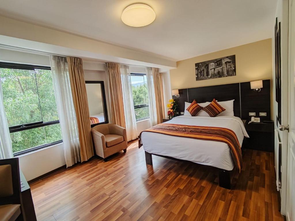een slaapkamer met een bed, een stoel en ramen bij Royal Inn Cusco Hotel in Cuzco