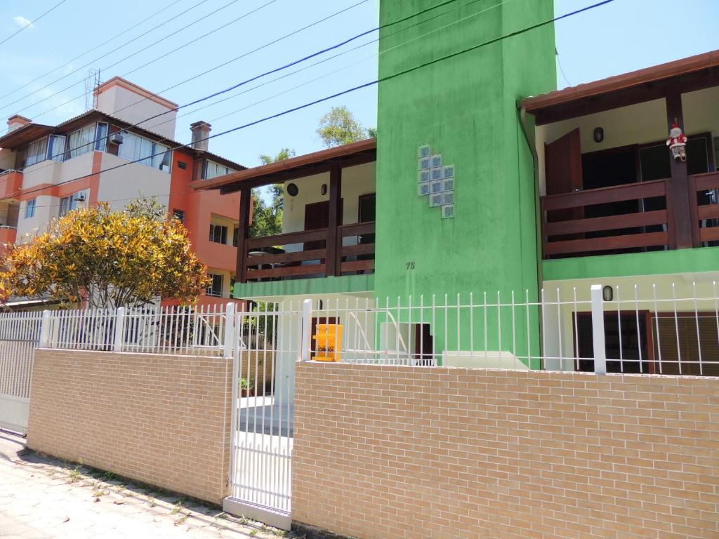 une clôture devant un bâtiment vert dans l'établissement POUSADA AZALÉIAS, à Florianópolis