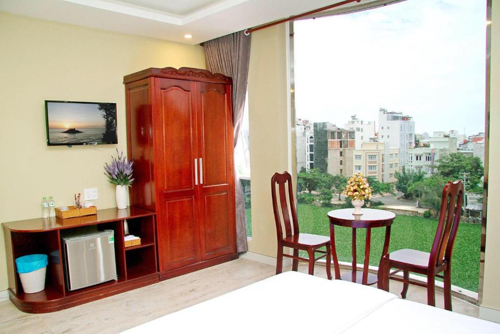 a bedroom with a bed and a table and a large window at Sea Memory Hotel in Vung Tau