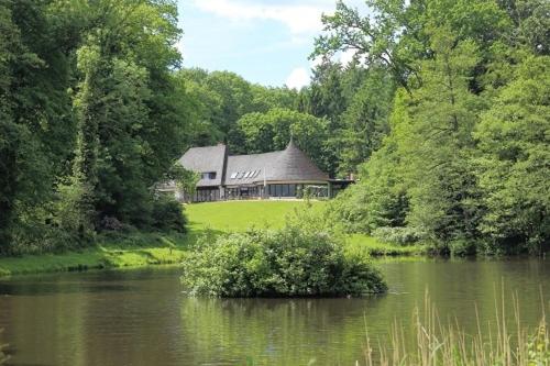 uma casa no meio de um lago com um arbusto em Forsthaus-Ferienhotel am Dobrock em Wingst