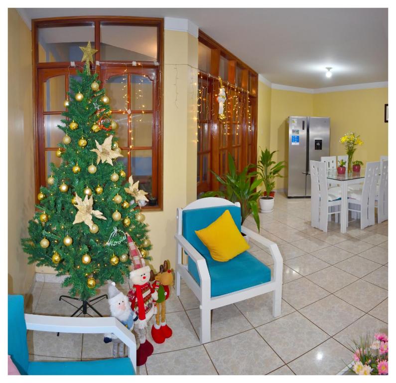 einen Weihnachtsbaum in einem Wohnzimmer mit einem blauen Stuhl in der Unterkunft Hospedaje La Casa Blanca in Urbanizacion Buenos Aires
