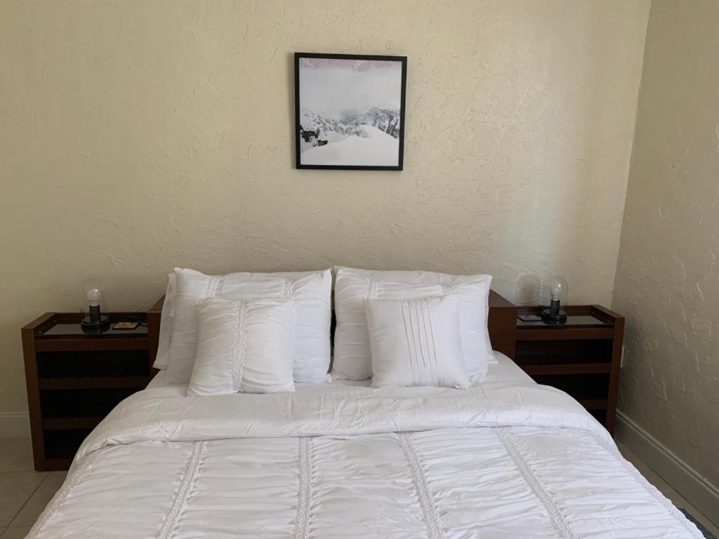 een bed met witte kussens en een foto aan de muur bij Cozy Private Room, near the Airport - Free parking - 01 in Miami