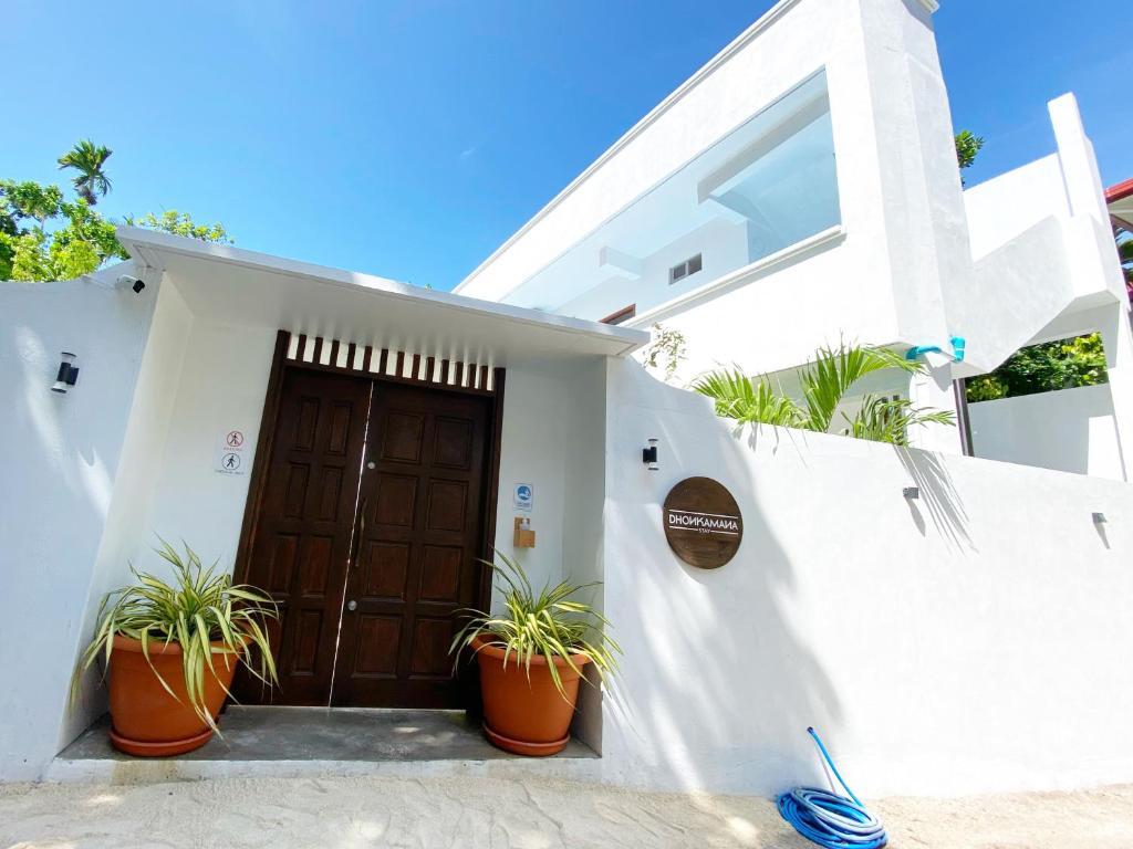 a white house with potted plants in front of a door at Dhonkamana Stay in Thoddoo