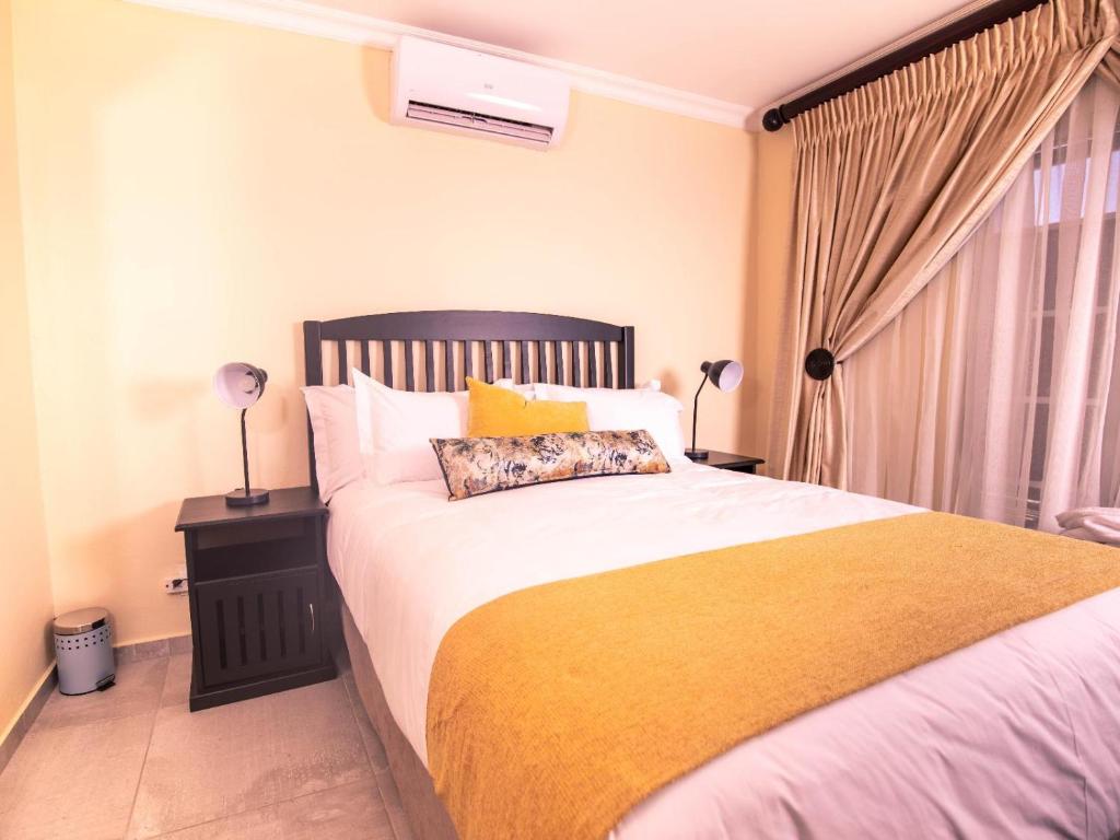 a bedroom with a large bed with a yellow blanket at Masingitana Hotel in Acornhoek