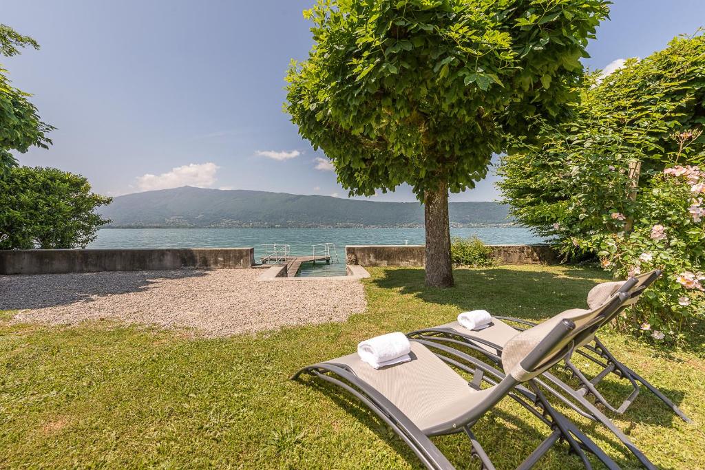 une chaise assise dans l'herbe à côté d'un arbre dans l'établissement Chalet de charme avec Ponton privé et Accès direct au lac, 4ch 8 pers, Exclusivité LLA Selections by Location lac Annecy, à Veyrier-du-Lac