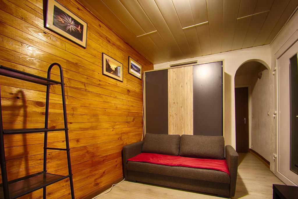 een kamer met een rode bank in een houten muur bij T1 situé à 100 m des thermes in Aix-les-Bains