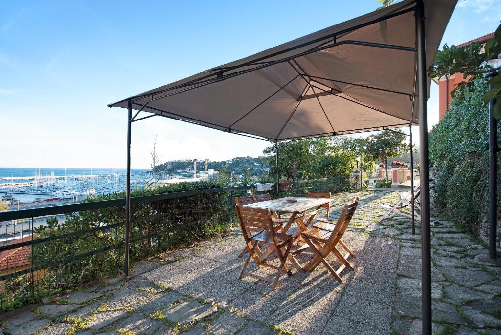 stół i krzesła pod parasolem na patio w obiekcie Trilocale in villa vista mare Apt 3 w mieście Varazze