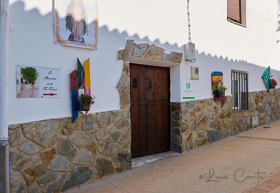 un edificio con puerta de madera y pared de piedra en El Almendro De La Tia Teresa, en Prados de Armijo
