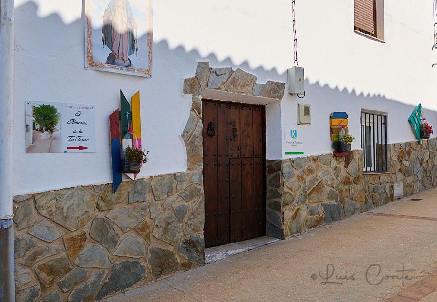 a building with a wooden door and a stone wall at El Almendro De La Tia Teresa in Prados de Armijo