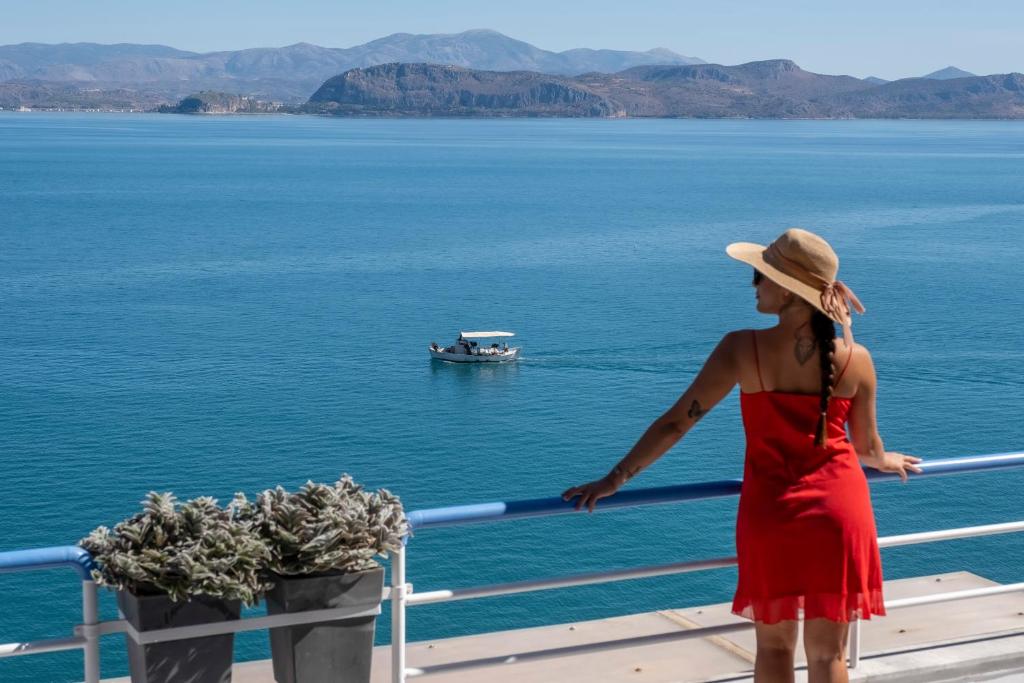 una mujer con un vestido rojo y un barco en el agua en Meli Apartments & Villas en Kivérion