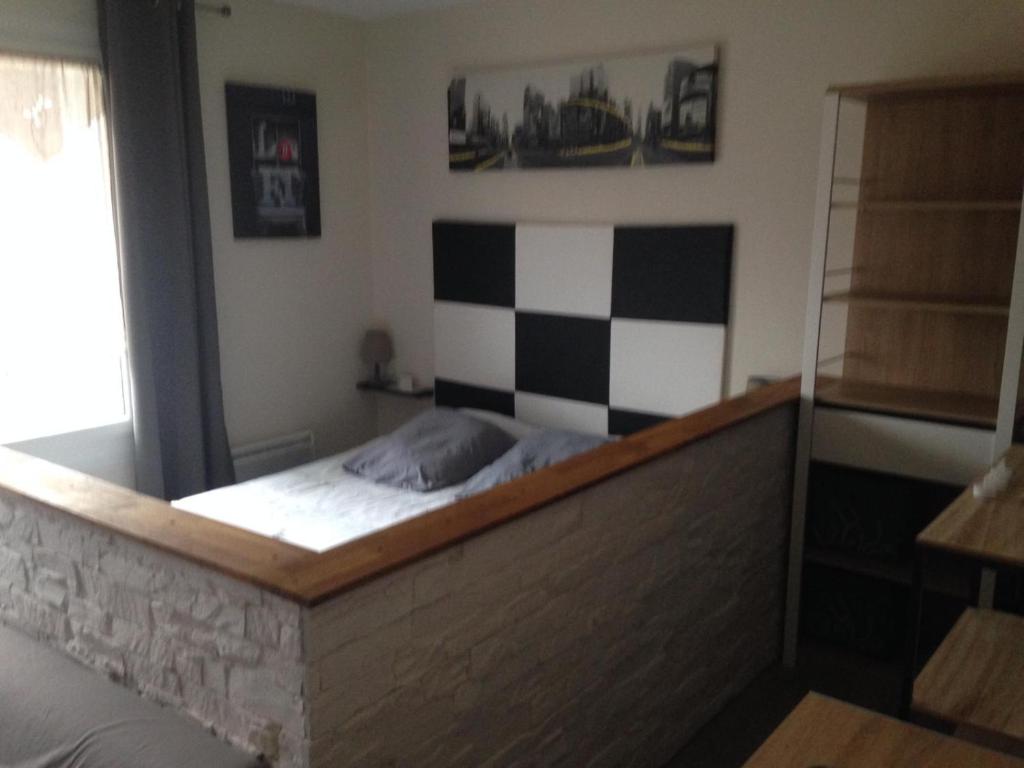 uma cama num quarto com uma parede xadrez em Studio très confortable em Limoges