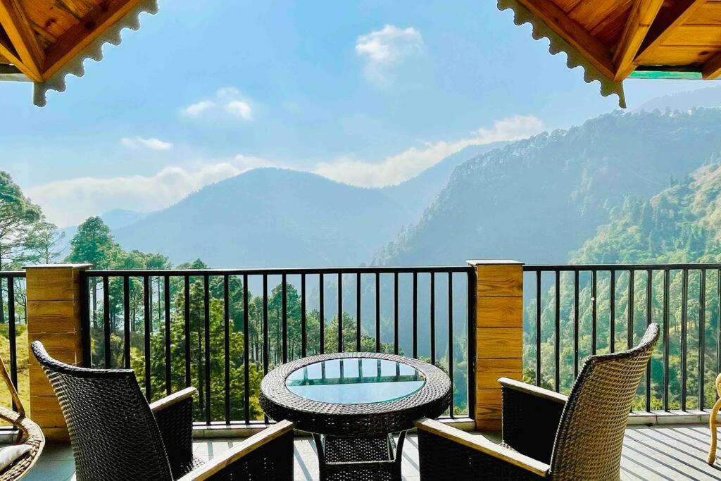 einen Balkon mit einem Tisch, Stühlen und Bergen in der Unterkunft The Country House in Nainital