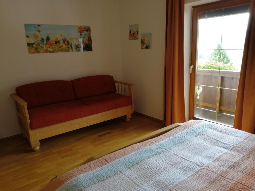 ein Schlafzimmer mit einem Sofa und einem großen Fenster in der Unterkunft Ferienhaus Sonnenseite in Weisspriach