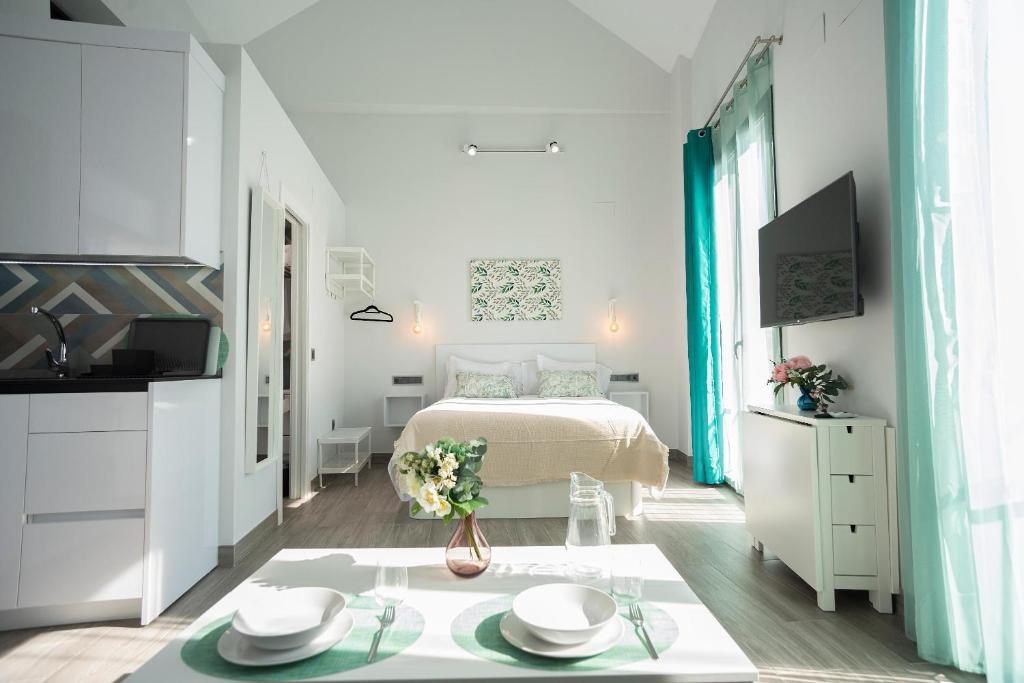 a small white bedroom with a bed and a table at EM21 Apartamentos in Córdoba