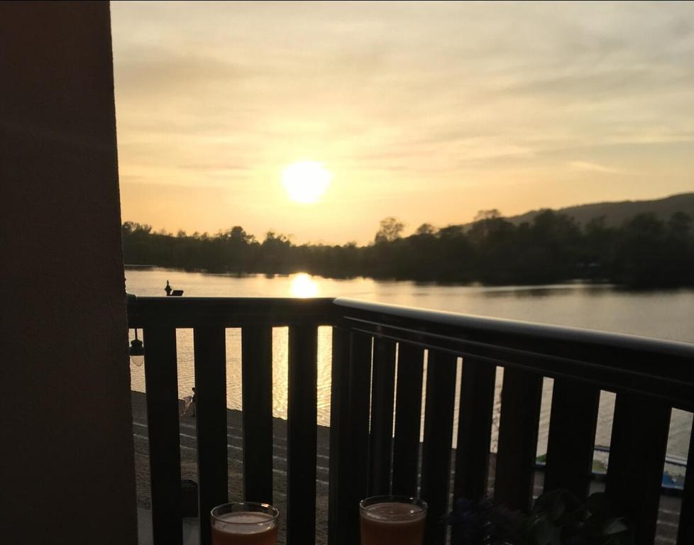 a view of the water from a balcony with the sunset at Apartman Darja sa pogledom na jezero in Ostrovo