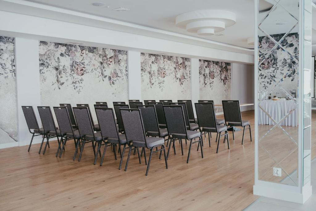 una fila de sillas en una habitación con papel pintado de flores en Gold Hotel, en Złotoryja