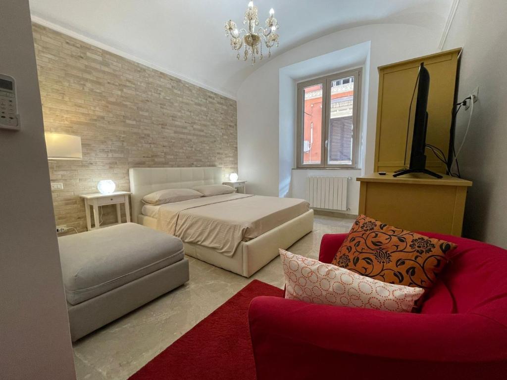 una camera con due letti e un divano rosso di Domus Enea - Colosseo Termini a Roma