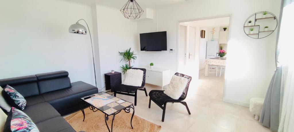 a living room with a black couch and chairs at Le Jardin Arlésien - Parking in Arles