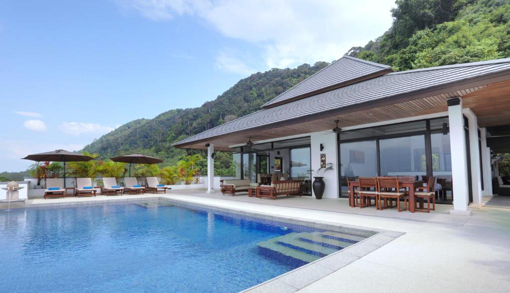a swimming pool next to a house with a mountain at Kulraya Villas - Luxury Serviced Pool Villas in Ko Lanta