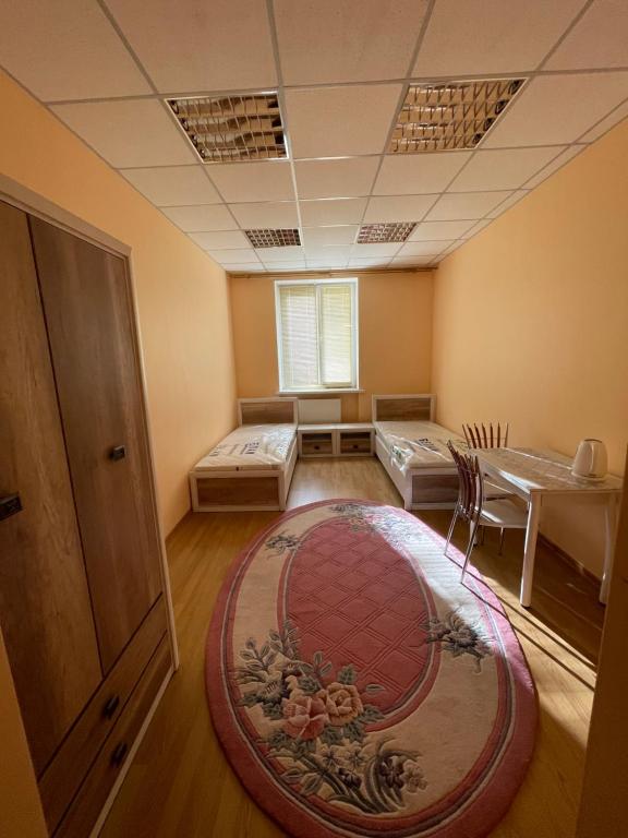 Habitación con 2 camas, mesa y alfombra. en Seven Hotel en Korostenʼ