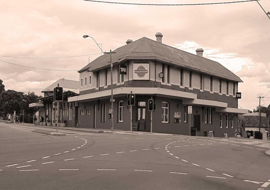 a black and white photo of a building on a street at The Beaconsfield Hotel in Fremantle