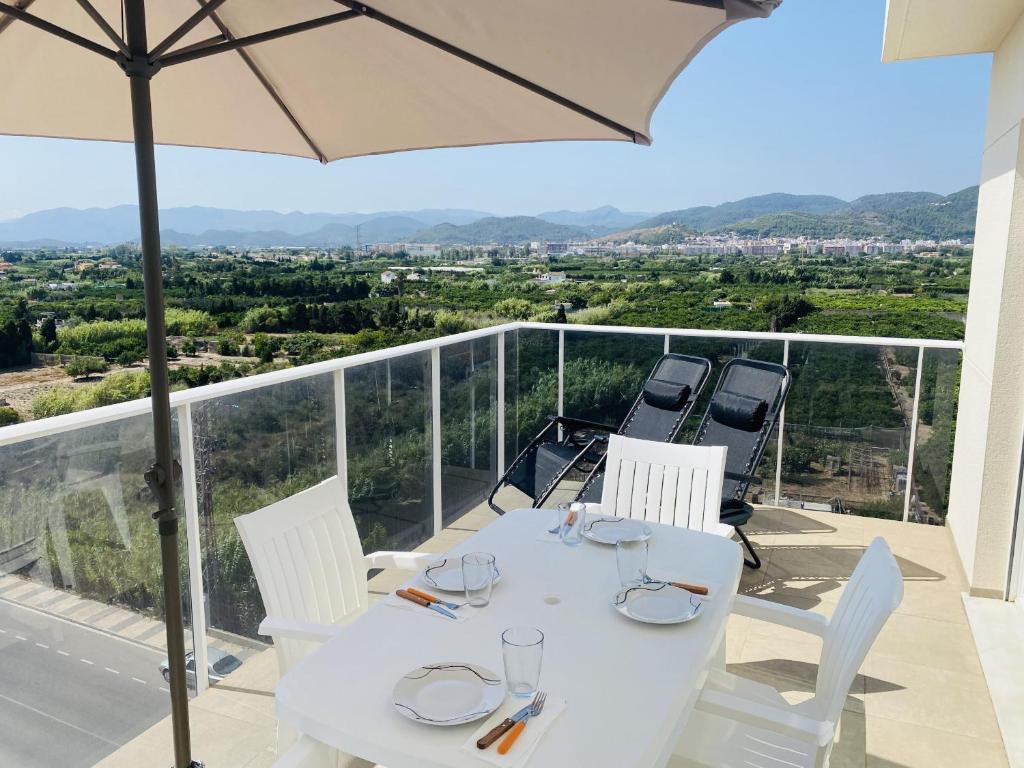 einen weißen Tisch und Stühle auf einem Balkon mit Sonnenschirm in der Unterkunft Anacasa Burguera Terranova AT601 in Oliva