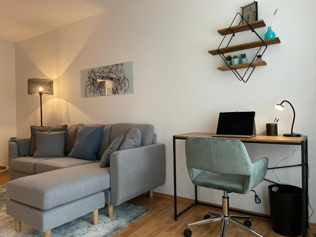 a living room with a couch and a desk with a laptop at LaMiaCasa Family Apartment near Bosch and Fair in Renningen