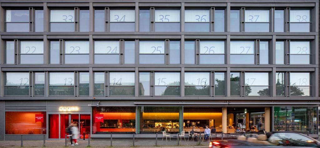 ein Gebäude mit vielen Fenstern und einem Auto davor in der Unterkunft Casa Camper Berlin in Berlin
