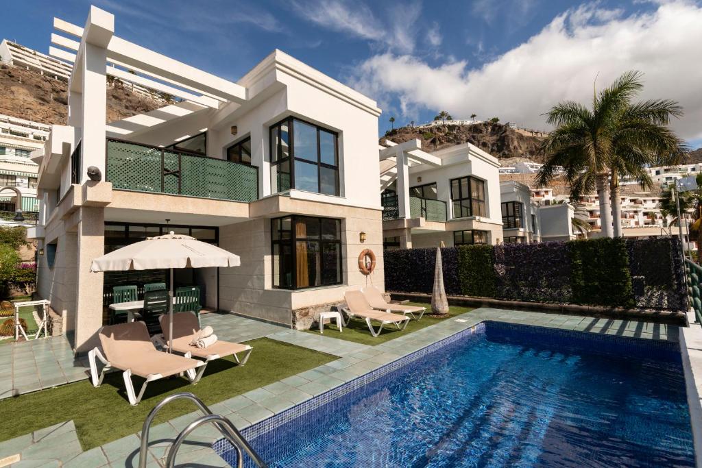 a villa with a swimming pool and a house at Sunshine Beach Villas in Puerto Rico de Gran Canaria