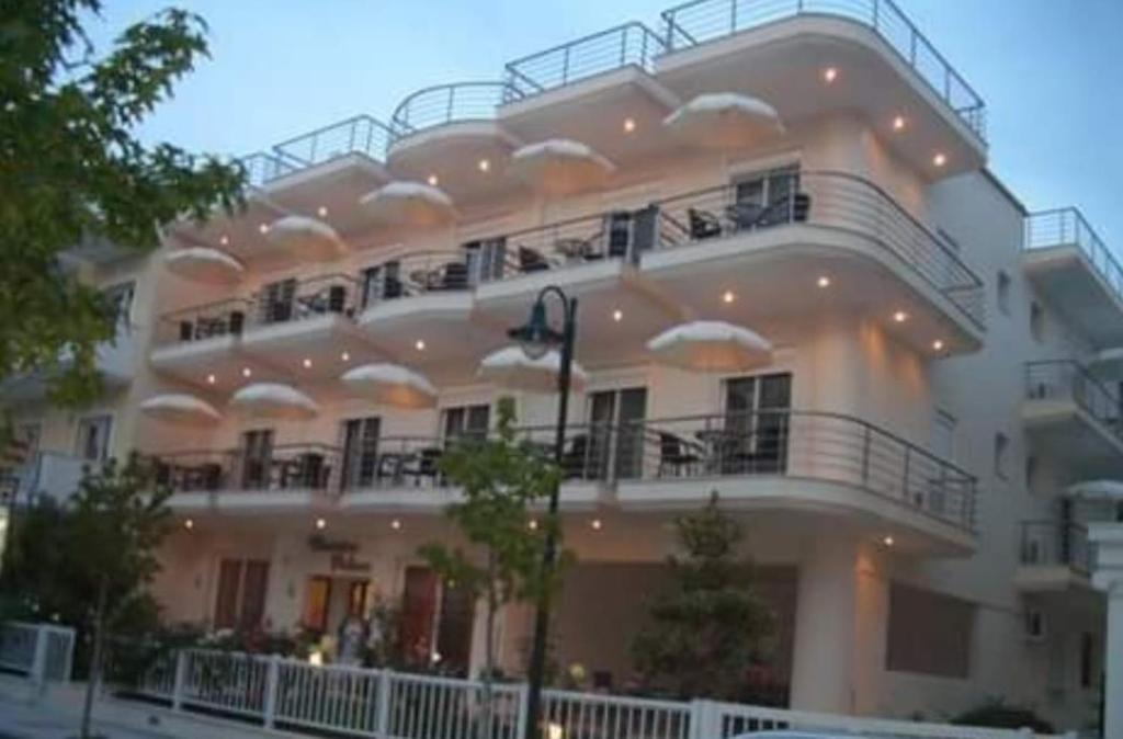 ein großes weißes Gebäude mit einem großen Balkon in der Unterkunft Christina Hotel in Olympiakí Aktí
