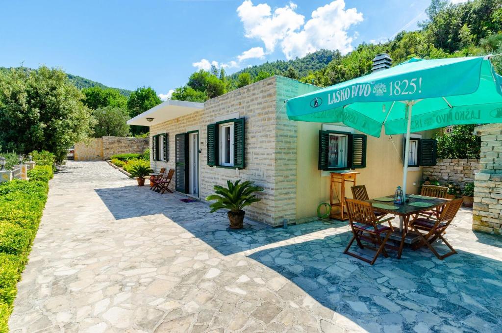 patio con tavolo e ombrellone verde di Vacation House Marija, Korčula a Korčula