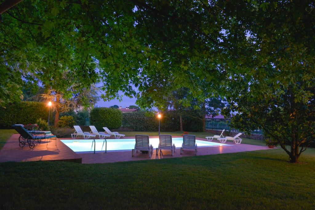 a group of chairs sitting around a pool at night at Agriturismo Kogoj in Medea