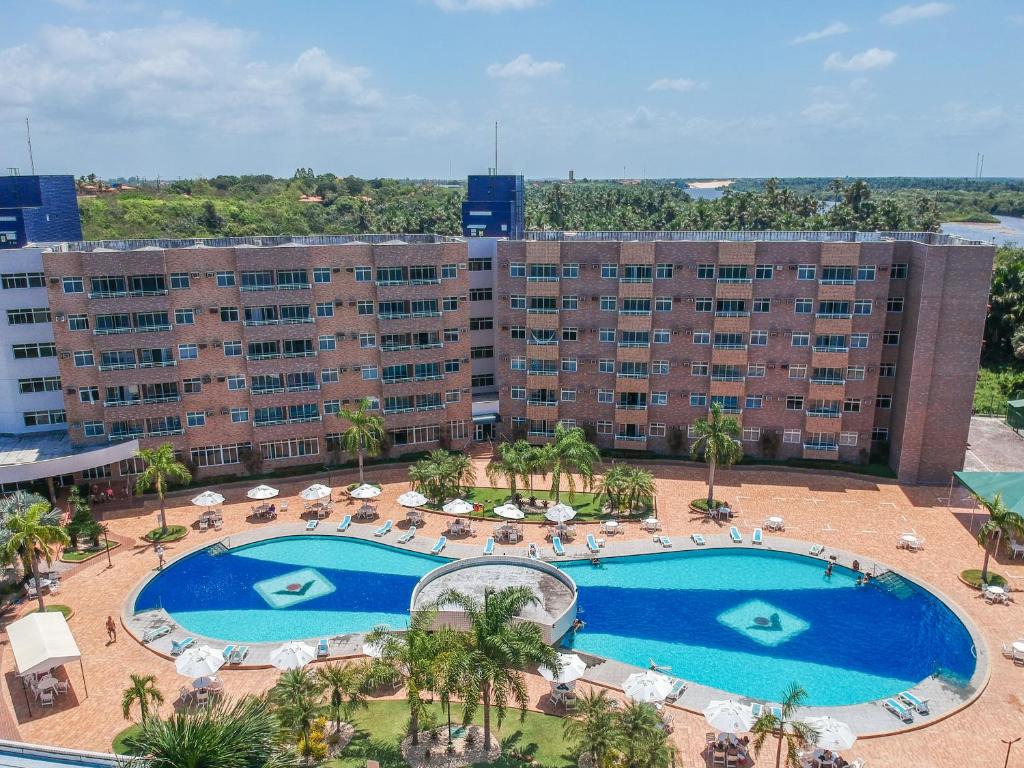 an overhead view of a large swimming pool with chairs and umbrellas at Gran Lençóis Flat Residence 2 suítes com sala in Barreirinhas