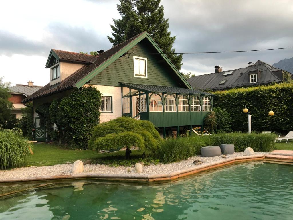 uma casa com um lago em frente em Haus mit Sauna und privatem Badeteich in Anif bei Salzburg em Anif