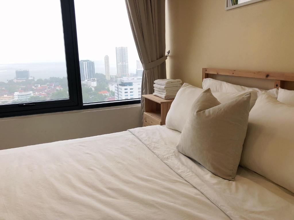 a bed with white sheets and pillows in a room with a window at Tropicana 218 Macalister Netflix Seaview in George Town
