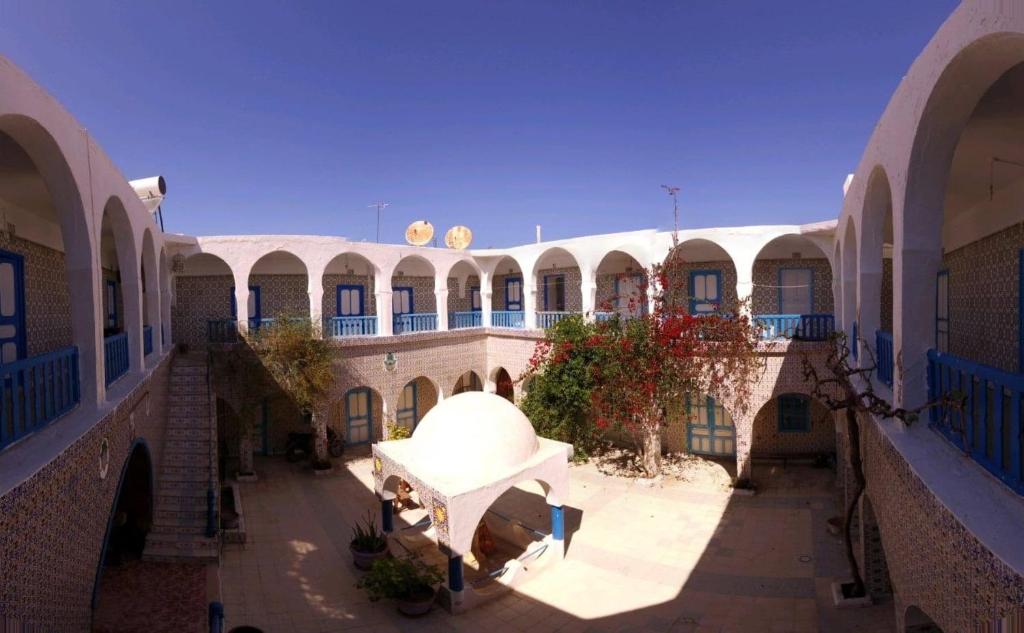an empty courtyard of a building with arches and a large building at Hôtel Sindbad in Houmt Souk