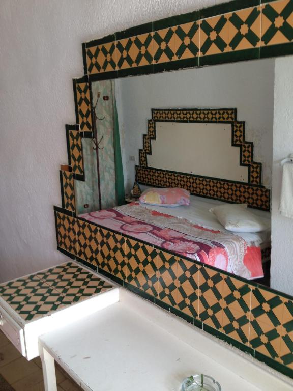a mirror above a bed in a room at Hôtel Sindbad in Houmt Souk