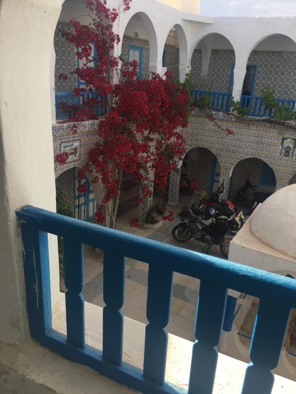 a balcony with a blue railing and red flowers at Hôtel Sindbad in Houmt Souk