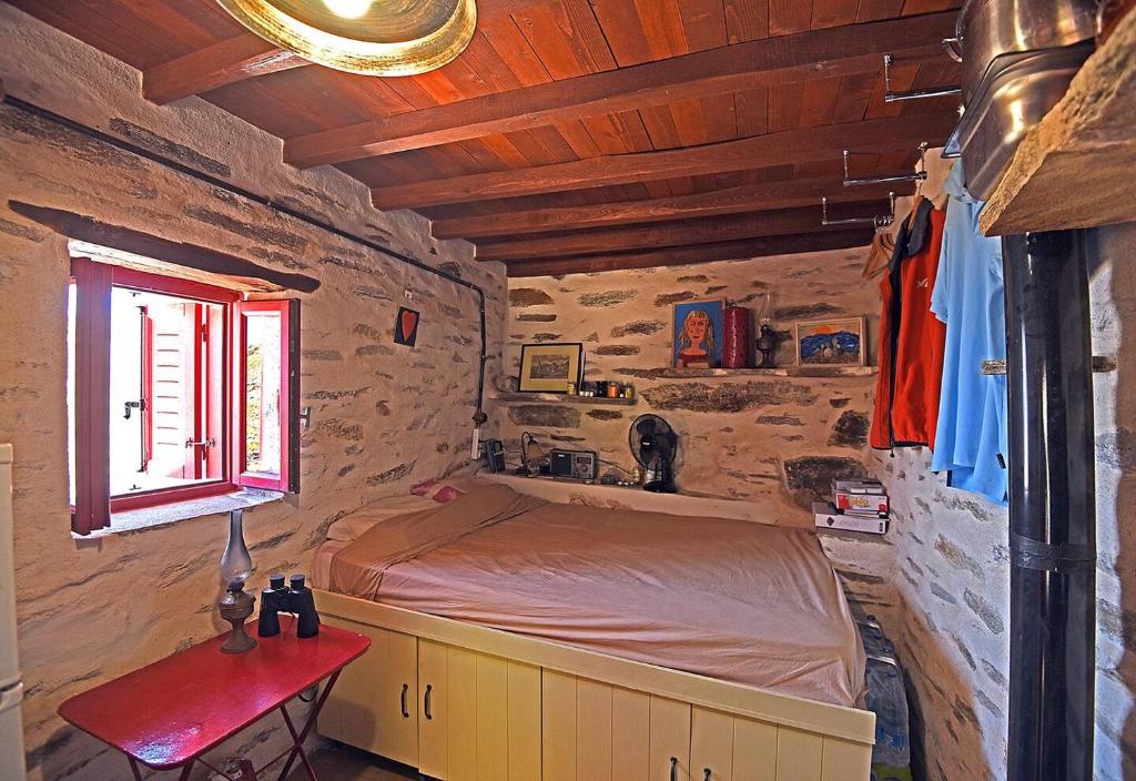 1 dormitorio con cama, mesa y ventana en Traditional stone house 1bedroom, sea view, Syros, en Ano Syros