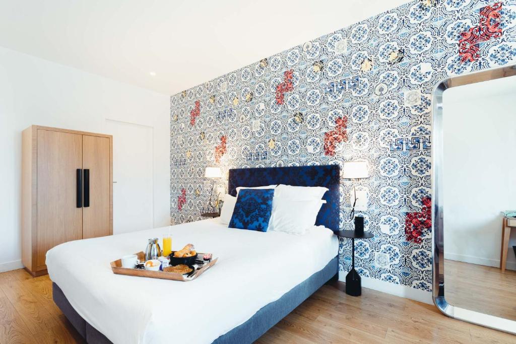 a bedroom with a bed with a tray of food on it at The Originals Boutique, Hôtel Le Lion, Clermont-Ferrand in Clermont-Ferrand