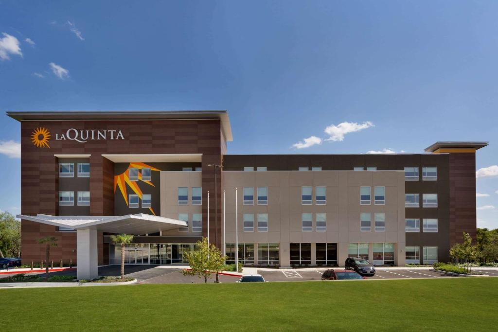 a hotel building with a lawn in front of it at La Quinta Inn & Suites by Wyndham San Antonio Seaworld LAFB in San Antonio