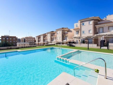 uma grande piscina em frente a alguns edifícios em Adosado obra nueva residencial de lujo em Santa Pola