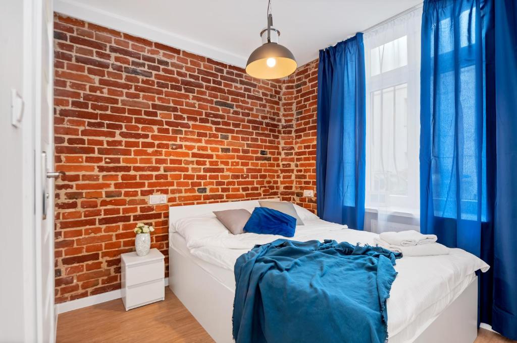 a bedroom with a brick wall and a bed at Drukarnia Apartments in Łódź
